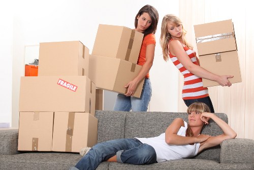 Professional movers carrying household items through a Kensington building